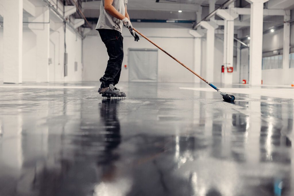 worker-applying-black-epoxy-resin-in-a-big-area Black epoxy resin in a large garage space